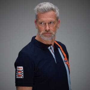Man in navy shirt with gray hair.